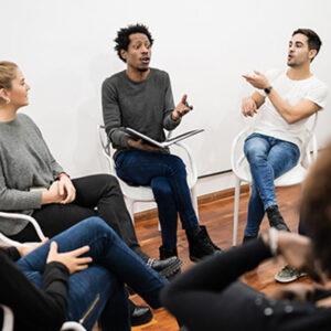 People seated in a circle, engaged in a motivational talk.